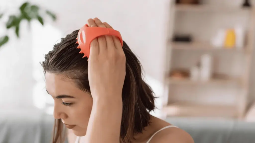woman-demonstrating-how-to-exfoliate-scalp-by-gently-massaging-her-head-with-fingertips-in-a-bright-bathroom-setting-1024x576-1 Kỹ thuật massage da đầu đúng cách để kích thích tuần hoàn máu
