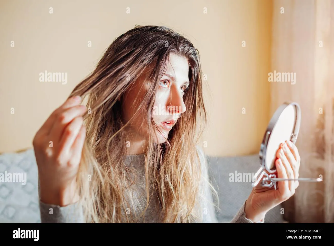 young-annoyed-woman-is-upset-about-dirty-oily-and-greasy-hair-looking-in-mirror-at-home-health-treatment-hair-care-products-selfcare-2pm8mcf Da đầu dầu không phải là đối tượng phù hợp để điều trị gàu bằng dầu dừa